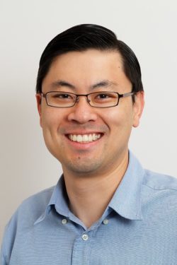 Head shot of Raymond Kuan, Chief Executive Officer of Canberra Imaging Group, smiling in a light blue shirt.